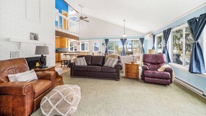 Un salón espacioso con chimenea, sofás de cuero, comedor y ventanas grandes con cortinas.