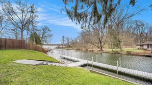 Una propiedad junto al río, con muelle, zonas de césped y valla de madera.