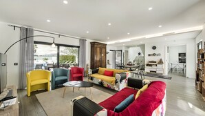 A modern living room with a sofa, chairs, a coffee table, and a dining area. - Villa Serena in Santa Luzia (Tavira)