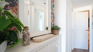 A hallway with a white dresser, a mirror, a plant, and a decorative basket. - Castelldefels - Apartment - Sleeps 4 - Beach Side (Castelldefels)