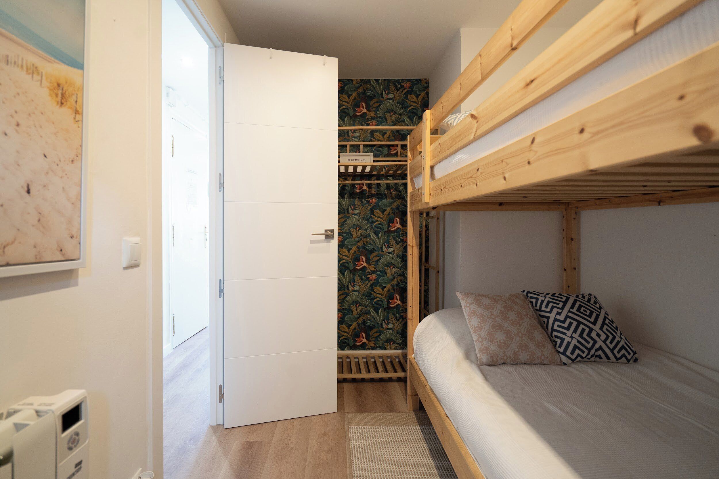 Een slaapkamer met een stapelbed, een houten hoofdbord, een klein nachtkastje en een behang met een patroon.