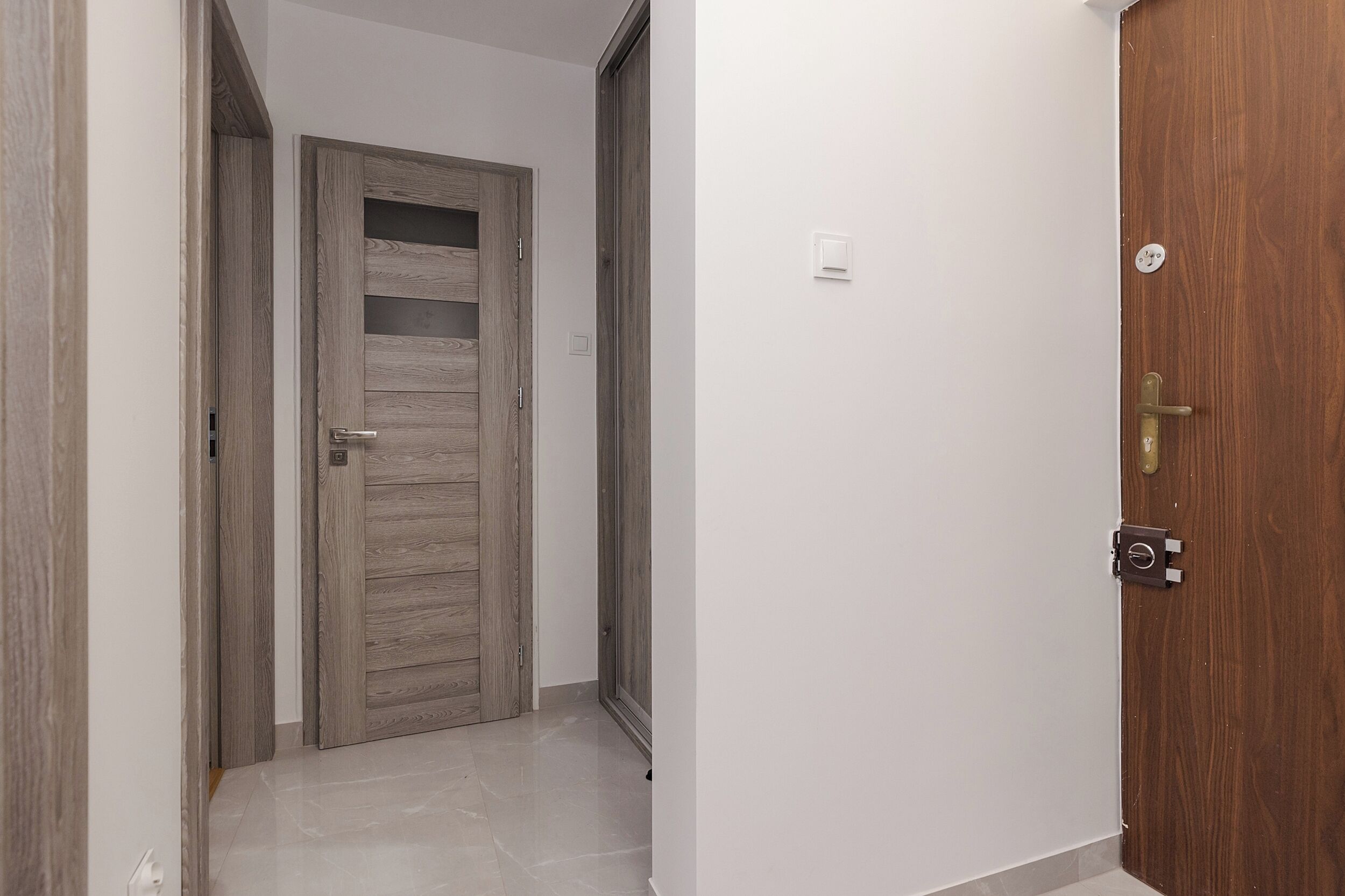 A hallway with a wooden door and a white wall.