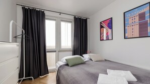 Ein Hotelzimmer mit einem Bett, einem Schminktisch, einem Fenster mit Vorhängen und zwei gerahmten Bildern an der Wand.