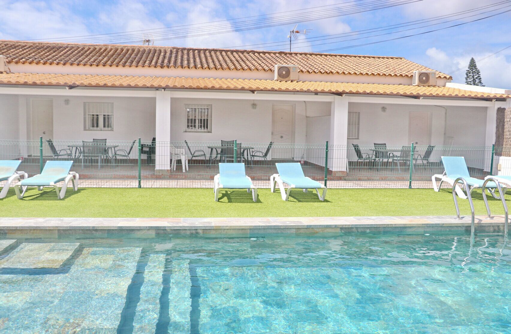 A poolside area with lounge chairs and a tiled roof.