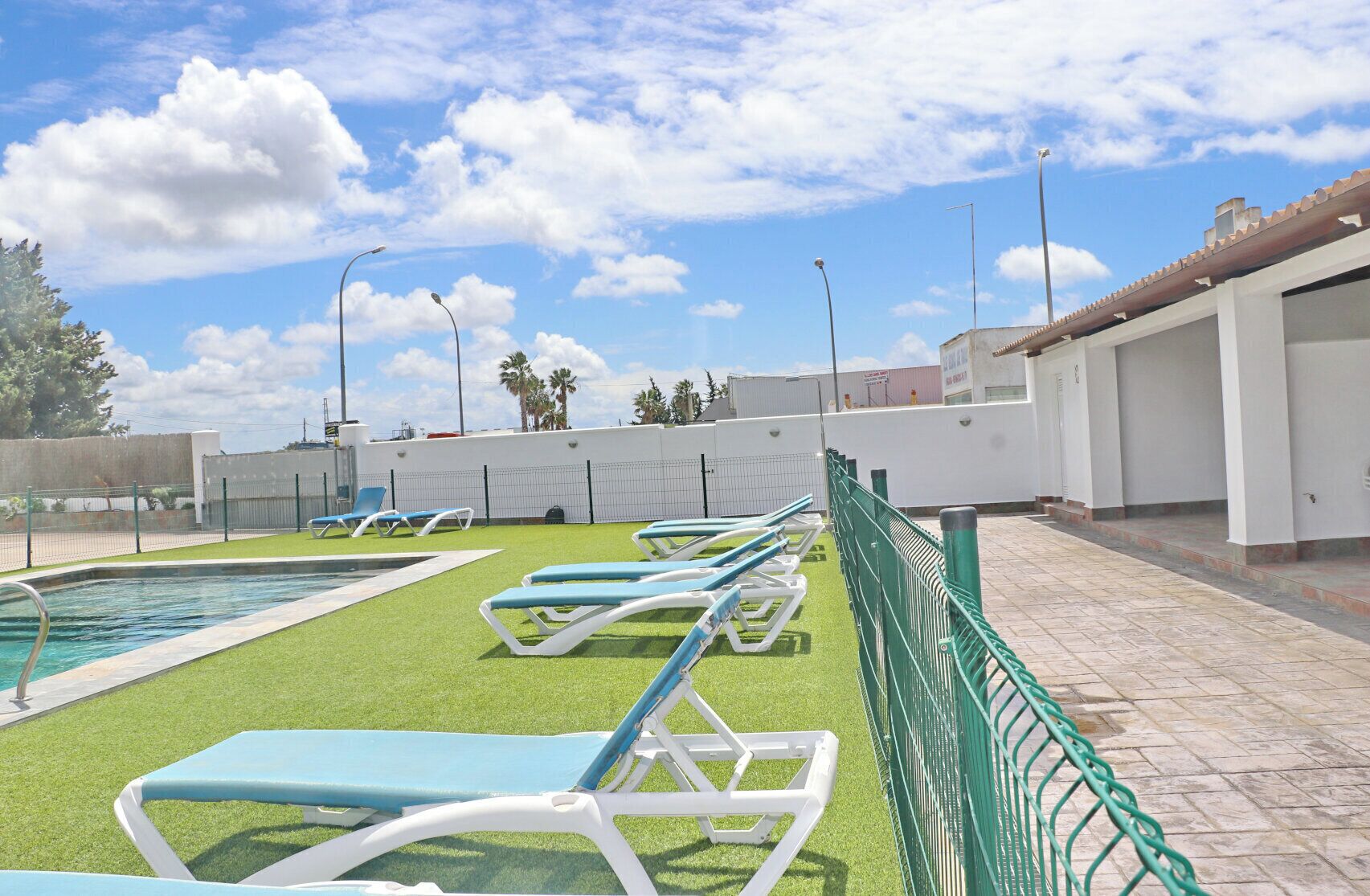 Zona de piscina en la azotea con varios sillones de tomar el sol y una piscina pequeña.