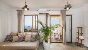 A living room with a sofa, a potted plant, and a dining area with a table and chairs. - Luxury 3 bedroom Villa with heated pool (Akrotiri)