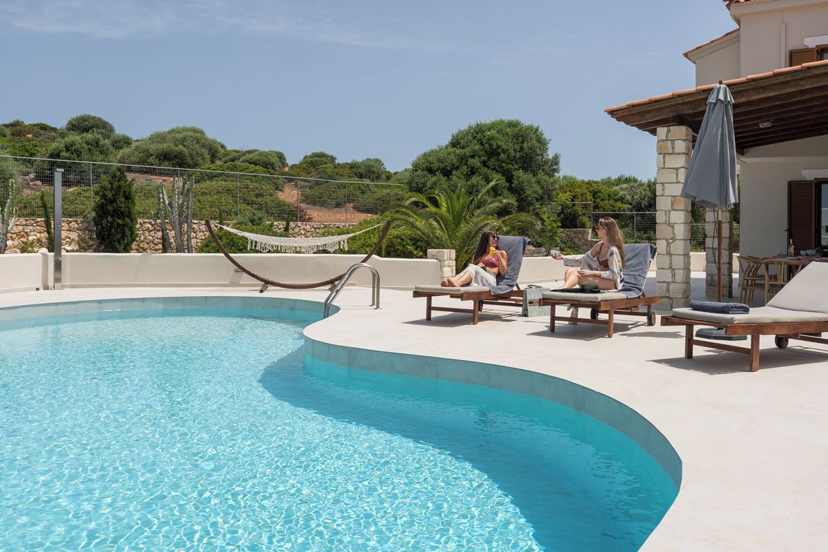 A pool area with lounge chairs and a hammock.