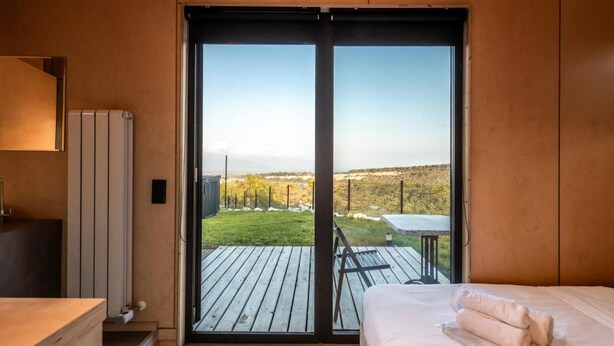 A bedroom with a large sliding glass door leading to an outdoor deck. - Roombox Kisiskhevi (Telavi)
