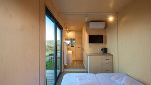 A modern hotel room with a large bed, a TV, a sink, and a view of the outdoors. - Roombox Kisiskhevi (Telavi)