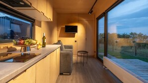 A modern kitchen with a built-in oven, a fruit bowl on the counter, and a television mounted on the wall. - Roombox Kisiskhevi (Telavi)