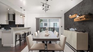 A modern kitchen with a dining area, featuring a central island, bar stools, and a large dining table. - Modern Luxury | Hot Tub | 4 Blocks to Mission Bay! (San Diego)