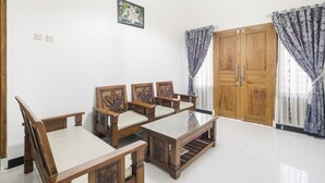 Un salon spacieux avec un ensemble de canapés en bois, une table basse avec un plateau en verre et une grande armoire en bois.
