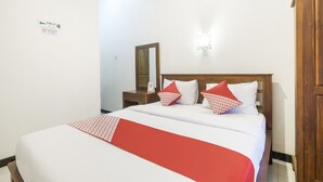 Une chambre d’hôtel avec un lit, une table de chevet, un miroir et une armoire en bois.