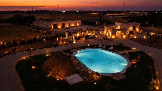 Un resort con piscina, mobiliario exterior y vista al atardecer.