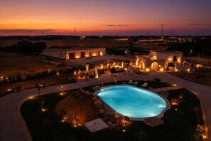 Ein Resort mit Pool, Sitzgelegenheiten im Freien und Blick auf den Sonnenuntergang.