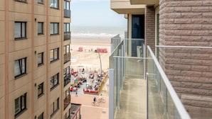 A high-rise building with a view of a beach and outdoor seating area. - 2-bedroom Flat With Side sea View (Koksijde)