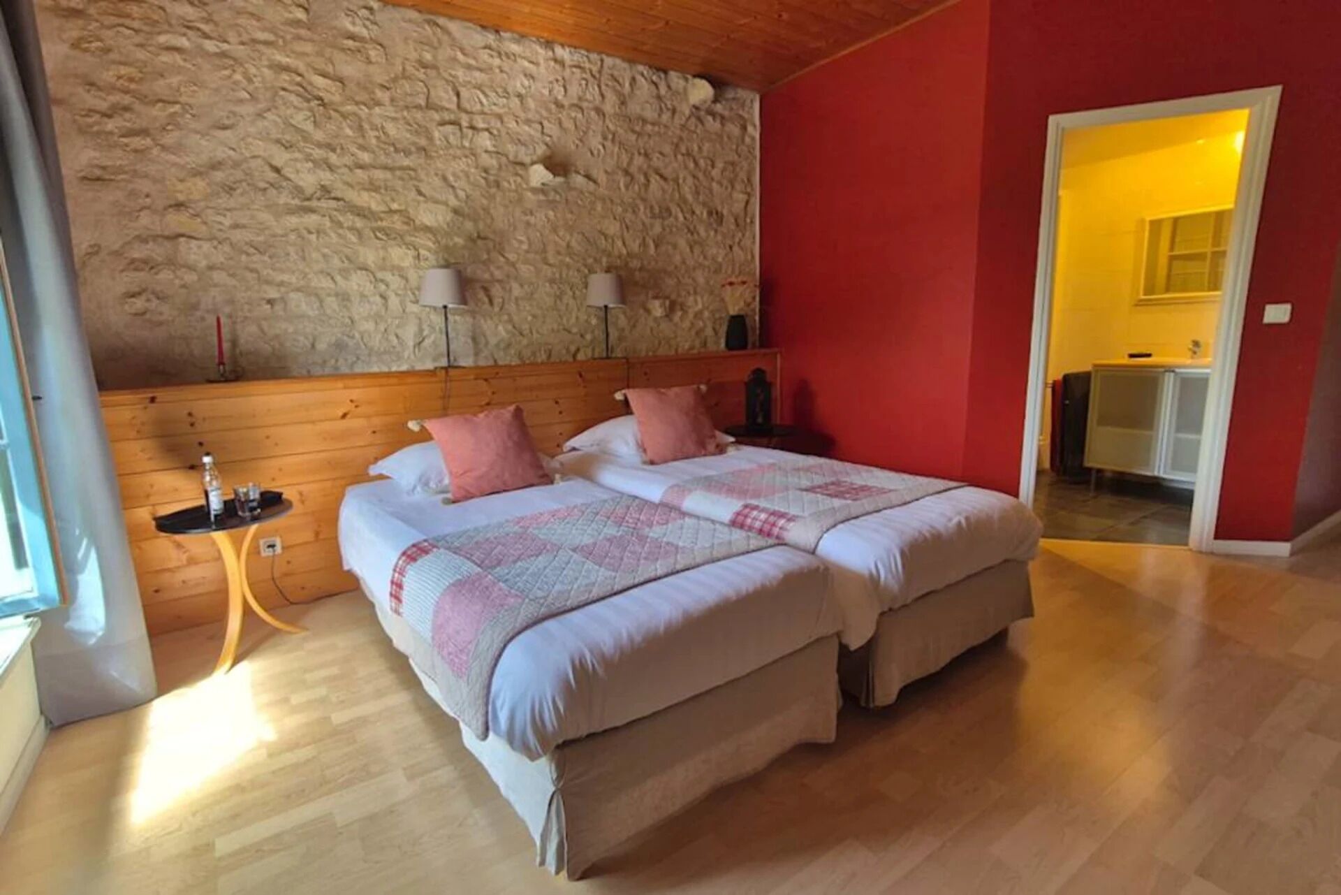 Ein Doppelbett mit Decke, ein Nachttisch, eine Lampe und eine Steinsäule.