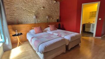 Ein Doppelbett mit Decke, ein Nachttisch, eine Lampe und eine Steinsäule.