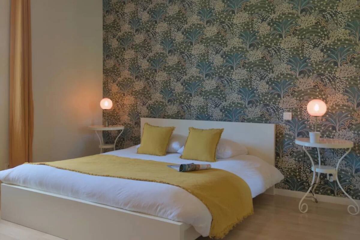 Ein Schlafzimmer mit einem Bett, zwei Nachttischen und einem Wandpapier mit Muster.