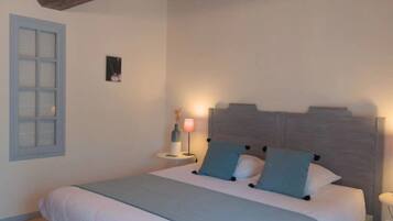 Une chambre à coucher avec un lit, une table de chevet, une lampe et une fenêtre donnant sur l’extérieur.