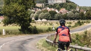 Ein Radfahrer auf einer Straße, im Hintergrund ein Schloss.