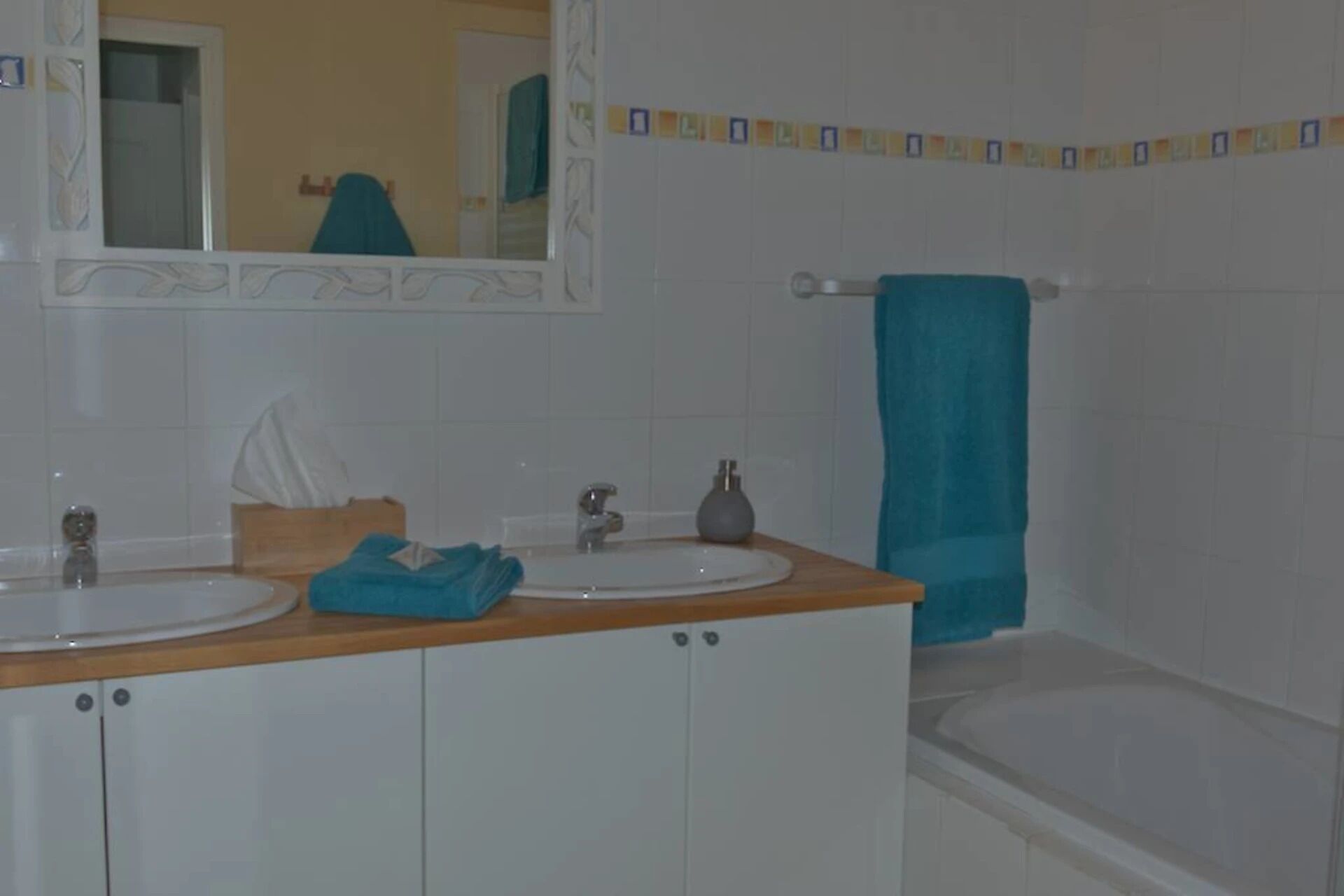 Een badkamer met twee wasbakken, een spiegel, een handdoekhouder en een bad.