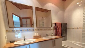 A bathroom with two sinks, a mirror, a bathtub, and tiled walls. - Le Tilleul de Ray (Ray-sur-Saone)