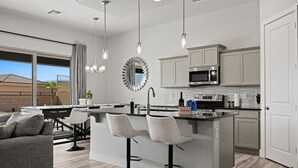 A modern kitchen with a central island, bar stools, and a dining area with a sofa.