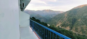 Un balcón con barandilla azul que da a un paisaje montañoso.