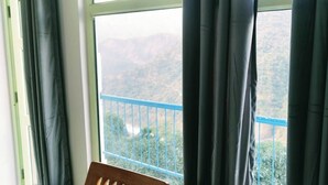A room with a view of a mountainous landscape through a balcony with a blue railing. - The Yamuna Deck Resort and Cafe (Dhanaulti)
