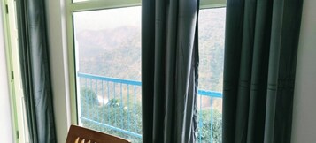 Habitación con vistas a un paisaje montañoso a través de un balcón con barandilla azul.