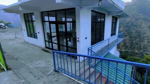 A small, single-story building with a balcony, surrounded by a mountainous landscape. - The Yamuna Deck Resort and Cafe (Dhanaulti)