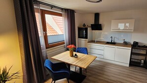 A compact kitchen with a wooden table, blue chairs, and a small dining area. - Elodia Luxury Apartment - Wi-Fi, Smart TV, Terrace, Kitchen, Towels (Heidenheim an der Brenz)