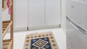 Moderni keittiö, jossa on valkoiset kaapit, kaasuliesi, pesuallas, kello ja jääkaappi.