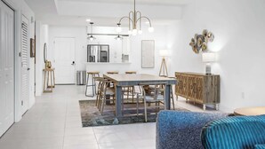Une cuisine moderne avec des meubles blancs, un îlot central et des luminaires suspendus.