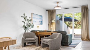 Un salon moderne avec un coin repas, une grande fenêtre avec des rideaux et une vue sur la verdure.