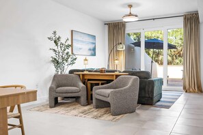 Un salon moderne avec un coin repas, une grande fenêtre avec des rideaux et une vue sur la verdure.