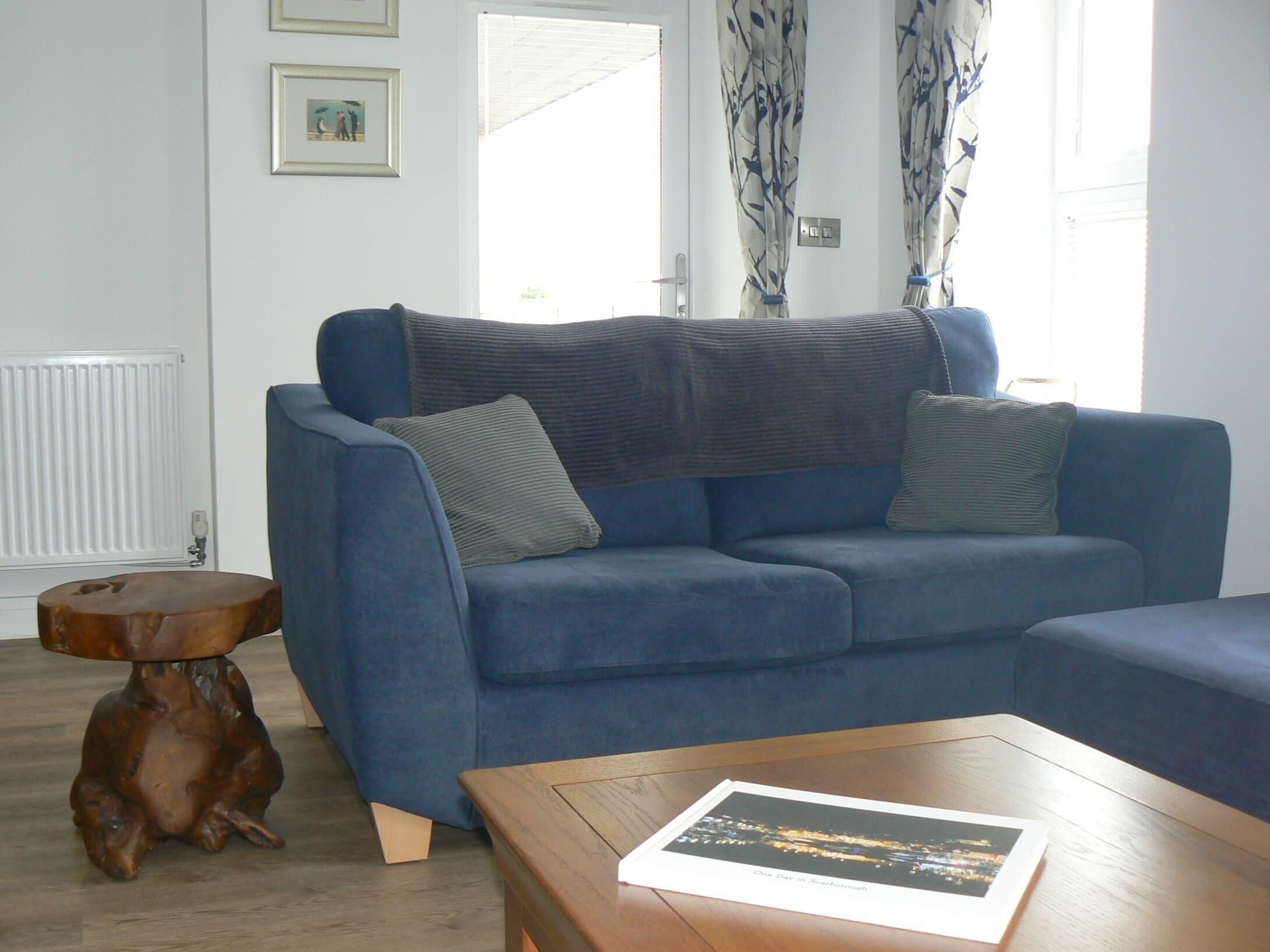 A living room with a blue sofa, a wooden coffee table, and a small wooden side table.