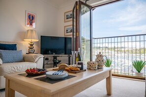 Relax in this stylish living room with a sofa, flat-screen TV, and coffee table, offering a scenic marina view.