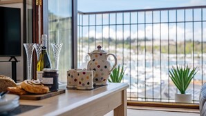 A kitchen counter with a coffee maker, teapot, and jars, overlooking a marina. - Coastal Escape with Balcony & River Dart Views (Kingswear)