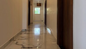 En hall med ett marmorgolv, trädörrar och infällda taklampor.