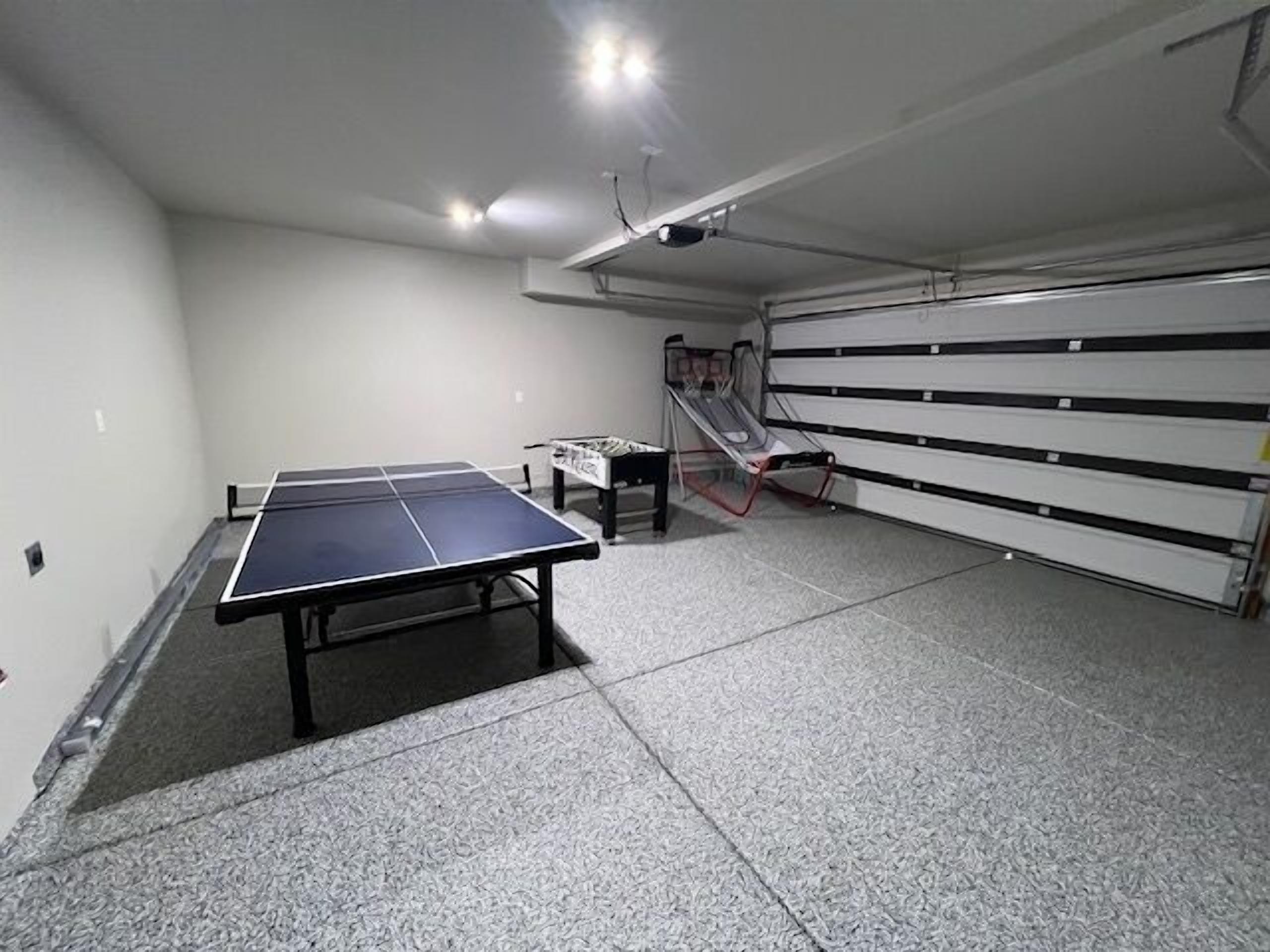 Ett rum med ett bordtennisbord, ett litet bord med ett brädspel och en rutschkana.