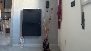 A room with a flat-screen TV mounted on the wall, a decorative plant, and a small stuffed toy on the floor. - Nicuzza House (Avola)
