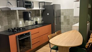 A modern kitchen with a central island, built-in appliances, and a dining area with a wooden table and chairs.