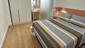 A bedroom with a bed, a bedside table, a lamp, and a wardrobe.