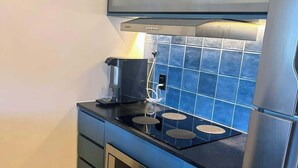 A compact kitchen with a built-in oven, a coffee maker, and a refrigerator.