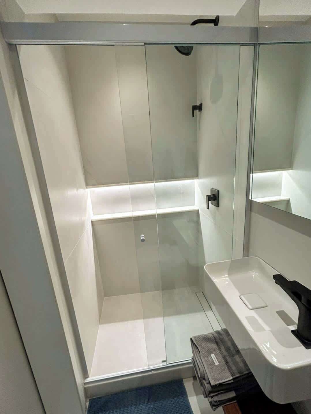 Une salle de bain moderne avec une douche à parois de verre, un lavabo blanc et un miroir.