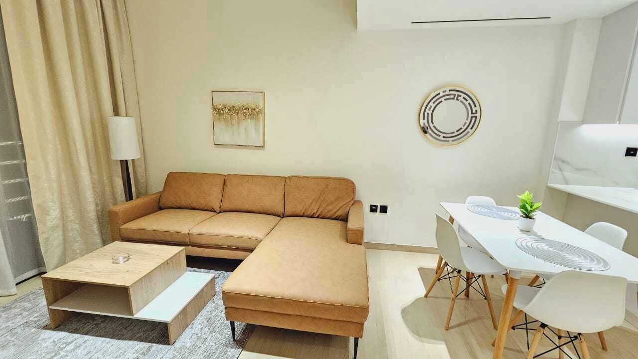 Ein modernes Wohnzimmer mit einer Eckcouch, einem Couchtisch, einem Esstisch mit Stühlen und einem dekorativen Spiegel an der Wand.