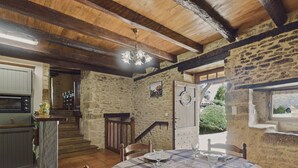 A rustic dining area with a stone wall, wooden beams, and a tiled floor.