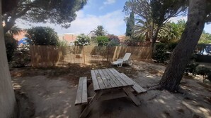 A backyard with a wooden picnic table and two white lounge chairs. - Fisherman's farmhouse between the swimming pool, the Etang de Salses-Leucate and the Mediterranean (Le Barcarès)